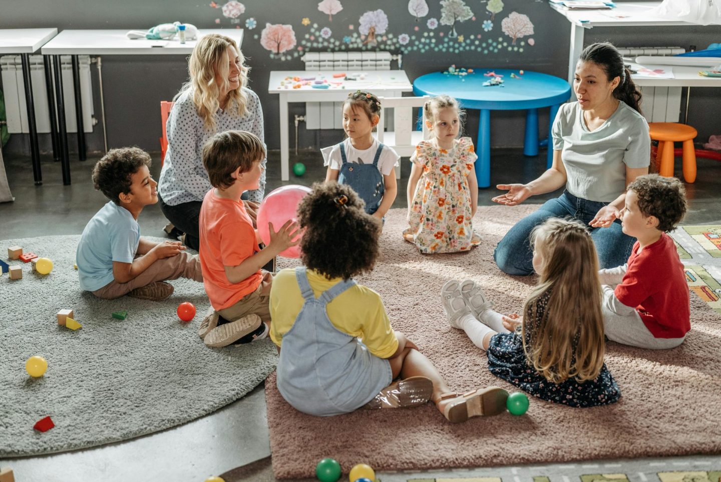 Des enfants réunis en cercle avec leurs enseignants, participant à une activité de classe de maternelle.