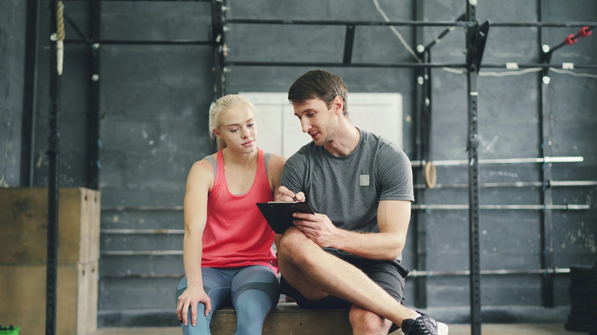 Trainer discusses progress with client using tablet in gym